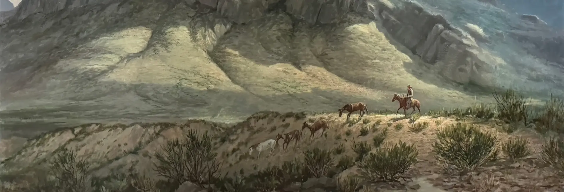 Cowboy on horseback leading a small herd along a dusty desert trail with dramatic canyon walls in the background.