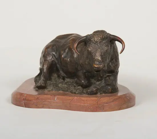 Bronze bull sculpture with curved horns on a round pink-marble base.