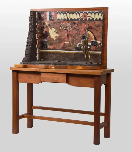 Wooden display table holding a large, framed painted panel showing ancient Egyptian figures and a small bronze statue in front of it.