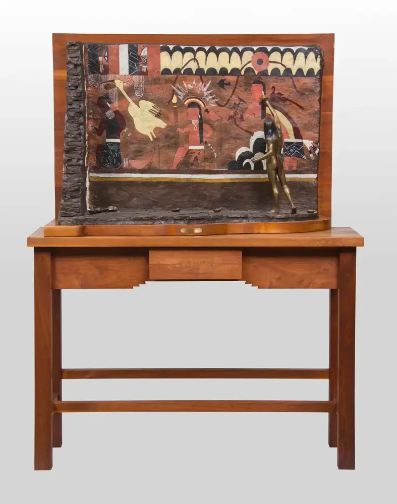 Framed mural on a wooden stand featuring stylized figures, with a bronze standing figure attached to the right side.