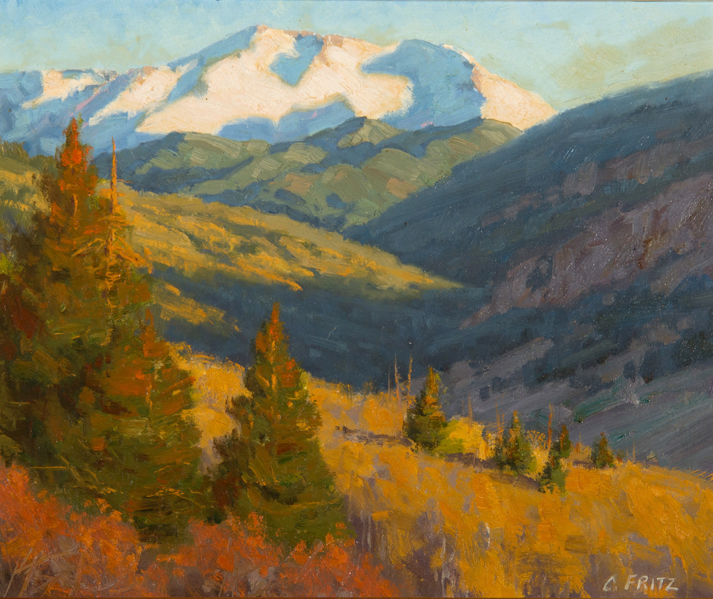Autumn mountain landscape: orange pines in foreground, gold grass, and blue-green slopes leading to snow-capped peaks under a pale sky.