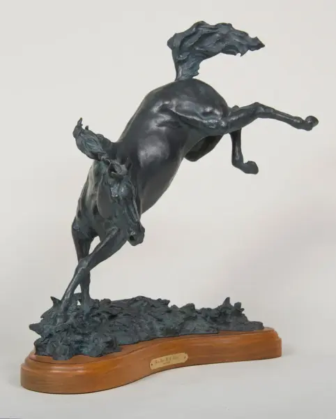 Bronze statue of a horse rearing on its hind legs, mounted on a wooden pedestal with a small plaque underneath.
