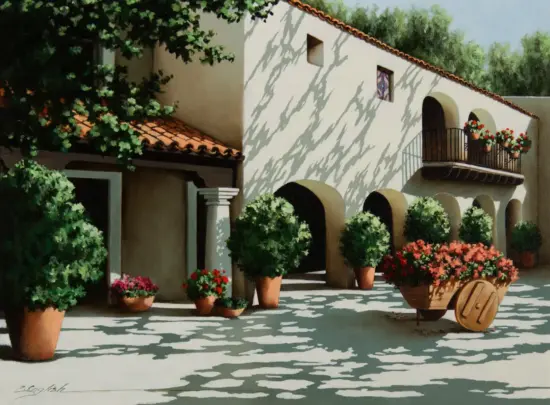 A sunlit Mediterranean courtyard with white stucco walls, arched doorways, and several potted plants along the walkway; a wooden wheelbarrow filled with red flowers sits in the foreground.