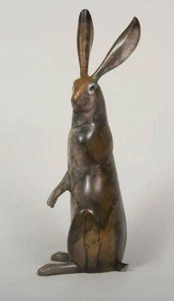 Bronze sculpture of a standing rabbit with long ears, seated on its hind legs.