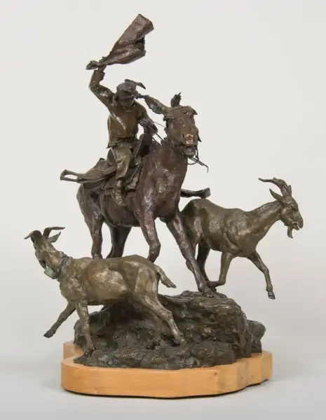 Bronze sculpture of a cowboy on a horse, raising a cloth as two goats stand at the rocky base on a wooden pedestal.