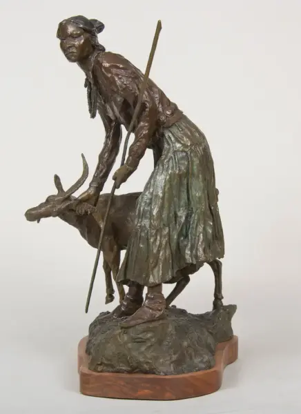 Bronze sculpture of a woman guiding a deer with a spear, atop a rocky base.