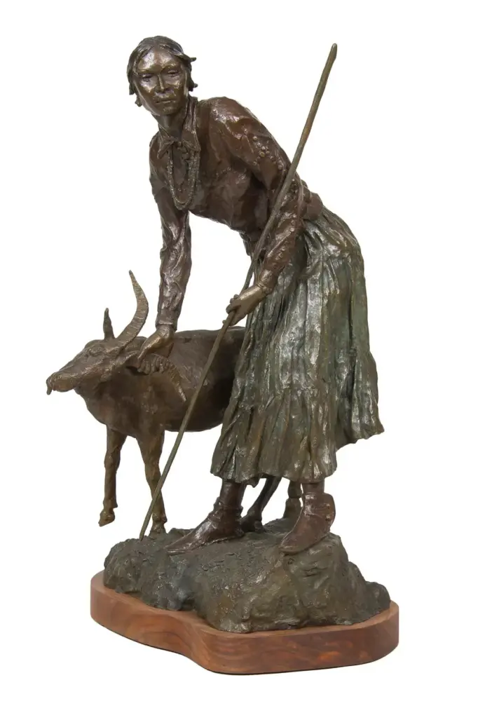 Bronze sculpture of a woman leaning on a staff beside a deer on a rocky base, mounted on a wooden plinth.