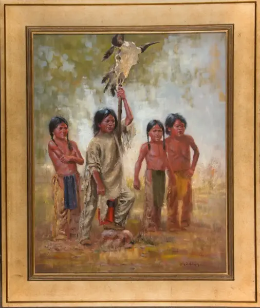 Indigenous man kneels and raises a feathered staff with an eagle on top, surrounded by four barefoot children watching.