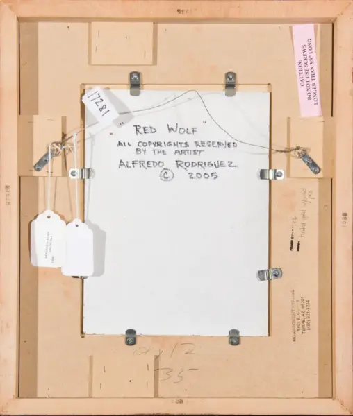 Back of a framed canvas showing handwritten title text, artist name, and multiple hanging hardware and labels on the frame edge.