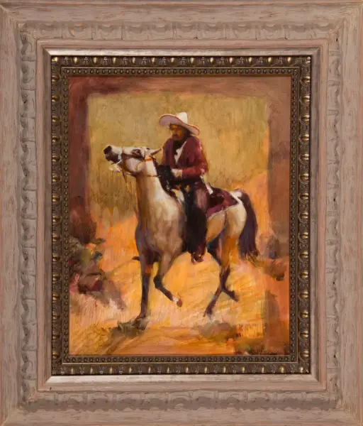 Cowboy wearing a white hat rides a horse through a warm desert landscape at sunset.
