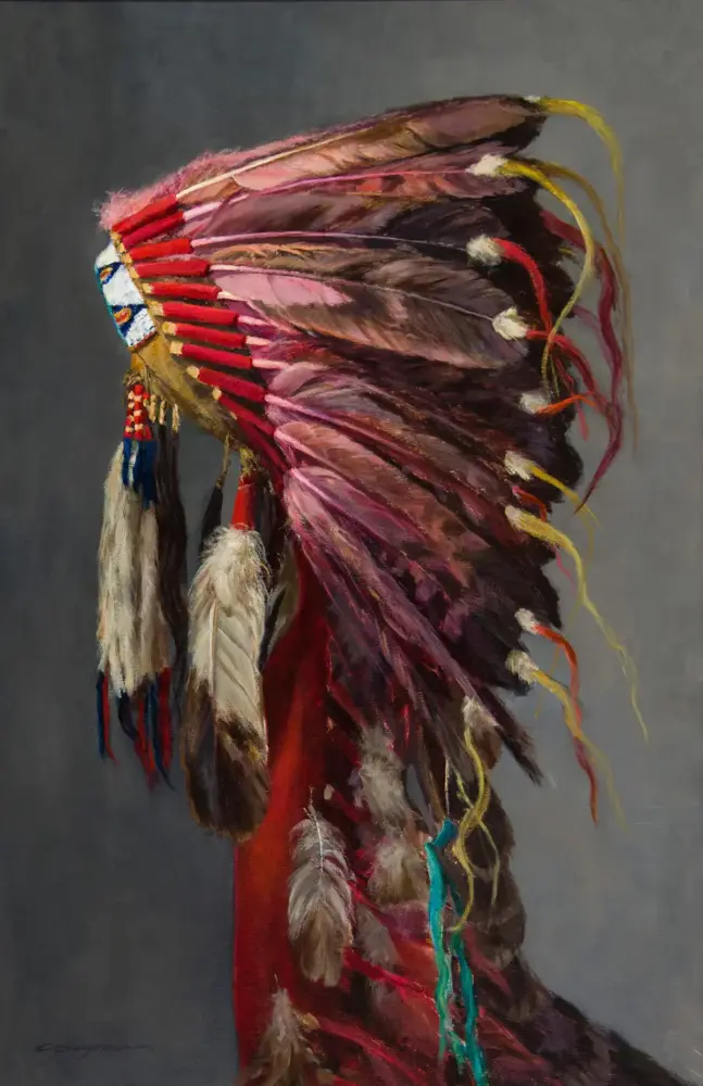 Person wearing a colorful feather headdress with red, pink, and yellow plumes against a gray backdrop.