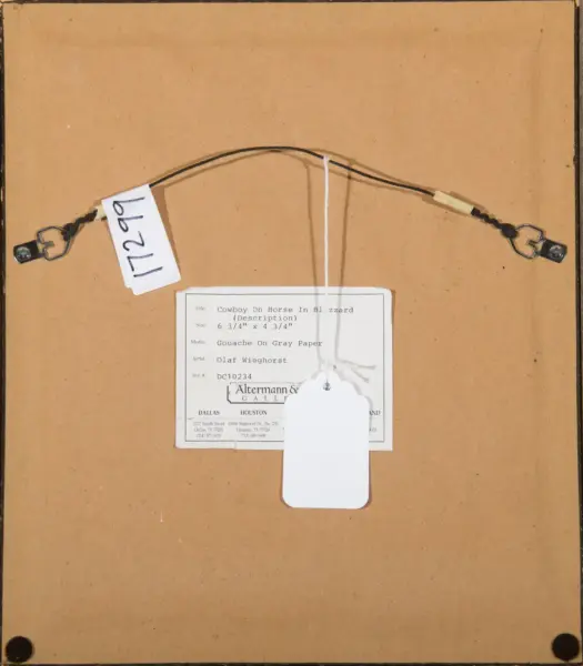 Back of a framed artwork showing a hanging wire attached to D-rings, with a white label bearing the title 'Cowboy On Horse In Blizzard' and a blank tag.