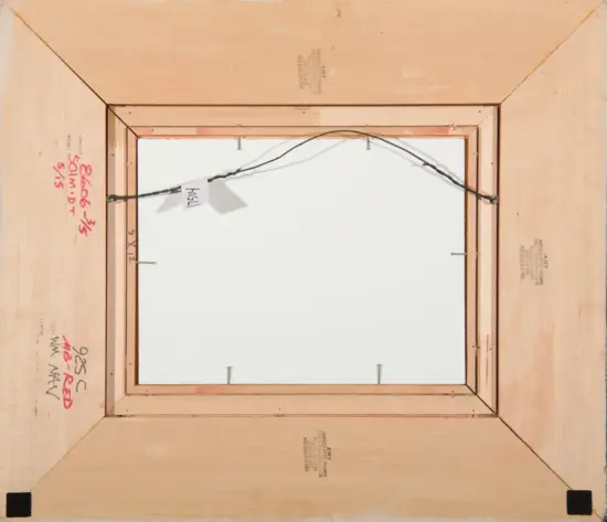 Back of a stretched canvas frame with hanging wire attached to side hooks; red handwritten notes and stamped markings on the wood edge.