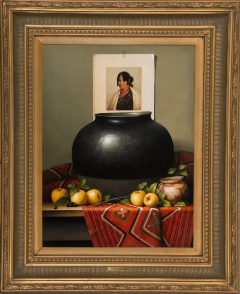 Ornate-framed still life: a large black pot on a table with apples and a red patterned cloth, and a small portrait behind the pot.