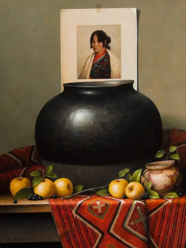 Large black ceramic vase sits on a table with apples and berries in front, and a small portrait framed behind it.