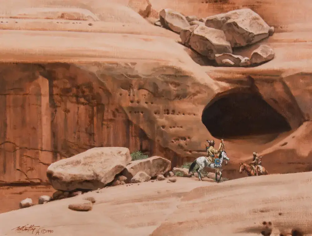 Three riders on horses approach a large dark cave in a red sandstone cliff, with boulders in the foreground.