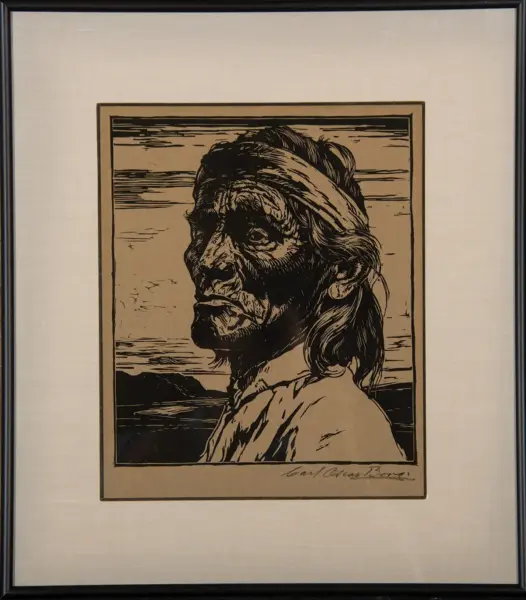 Framed beige mat with a woodcut-style profile portrait of a Native American man wearing a headband.