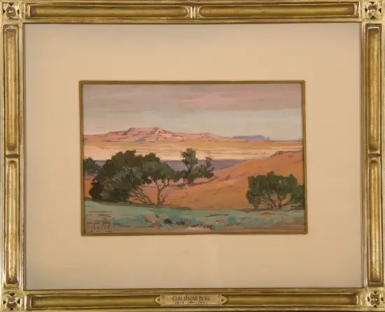Desert landscape painting with orange sand dunes, green shrubs, and distant mesas in a gold ornate frame; signed Carl Oscar Borg.