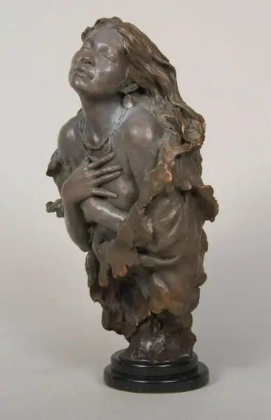 Bronze sculpture of a woman with eyes closed, hands crossed over her chest and flowing hair, on a round pedestal.