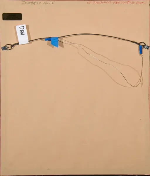 Back of a framed piece showing a long wire running across the back, secured with blue tape and metal endpoints, plus a white tag with handwritten numbers on the left.