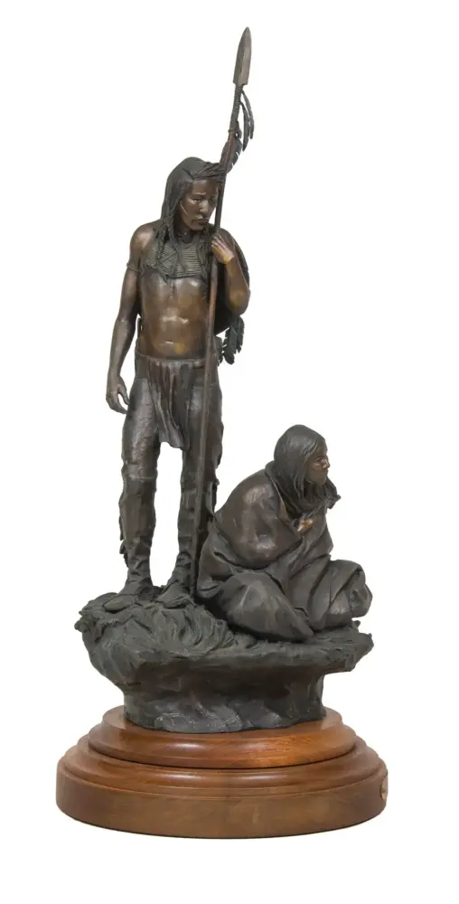 Bronze sculpture of a standing Indigenous man with a spear and a seated woman on a rocky base, mounted on a wooden pedestal.