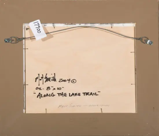 Back of a framed painting showing hanging wire and a white label, with handwritten title 'Along the Lake Trail' and size '8x10' (artist signature/date faint).