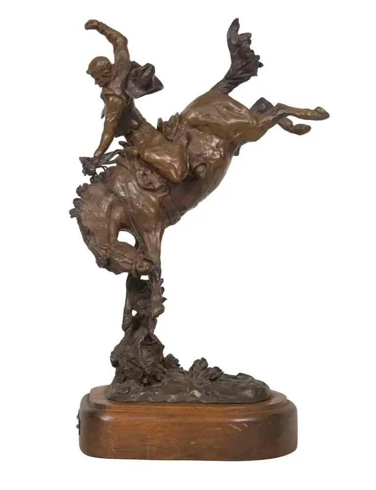 Bronze sculpture of a rider on a rearing horse mounted on a wooden base, captured in dynamic motion.