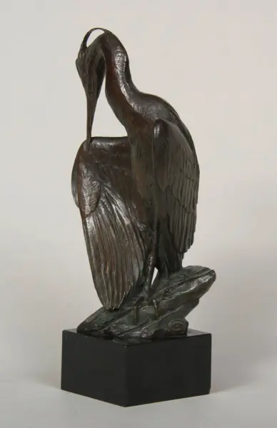 Bronze sculpture of a heron with a curved neck, perched on a black square pedestal.