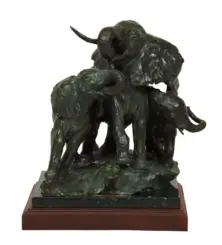 Bronze sculpture of three elephants with trunks raised, perched on a dark stone base atop a wooden plinth.