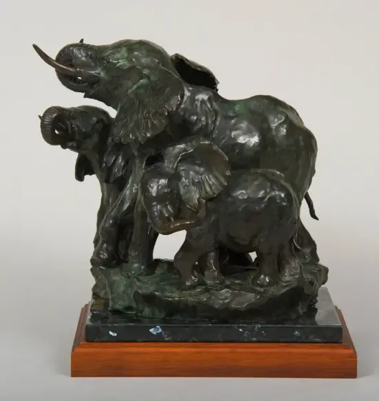 Bronze sculpture of an adult elephant and a calf with trunks raised, on a dark marble pedestal with a wooden base.