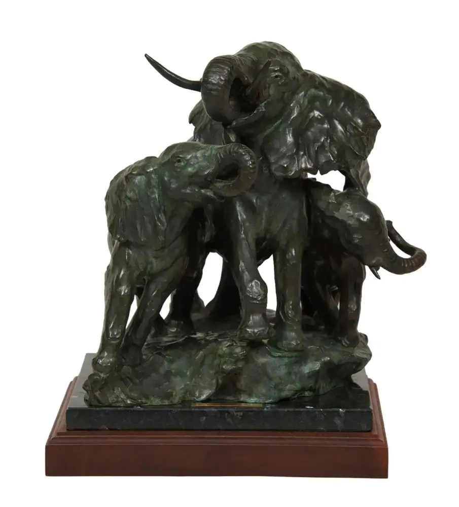 Bronze sculpture of three elephants with trunks raised, perched on a dark stone base atop a wooden plinth.