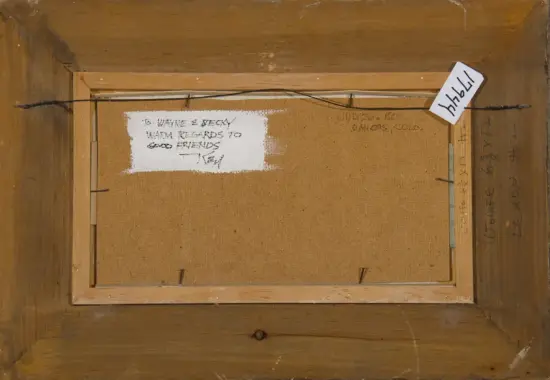 Back of a stretched canvas in a wooden frame, with a hanging wire across the top, a white painted label on the left, and handwritten notes on the right side of the burlap backing.