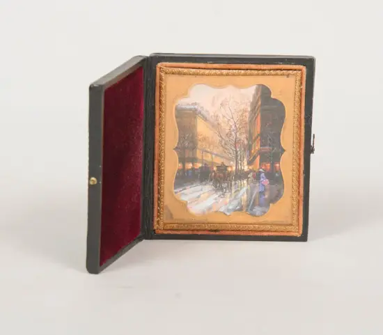Miniature painting in an ornate gold frame inside a black hinged box with red velvet lining; winter street scene with horse-drawn carriages.