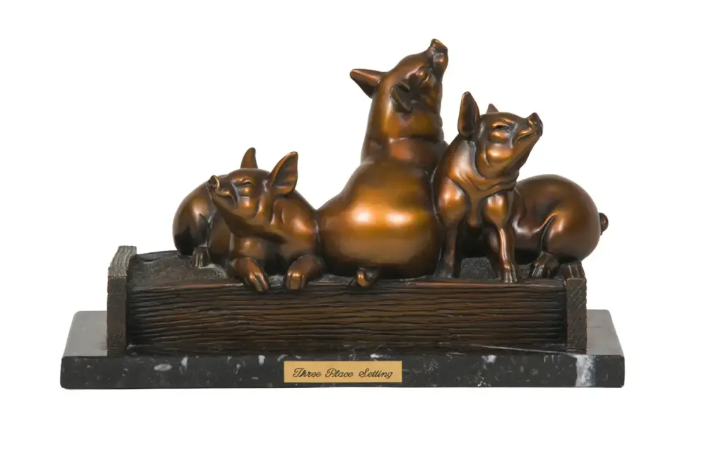 Bronze sculpture of three pigs lounging on a wooden log base with a plaque that reads 'Three Place Setting'