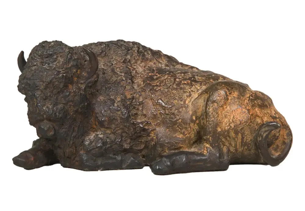 Bronze sculpture of a reclining buffalo with a textured, rough surface and curled horns.