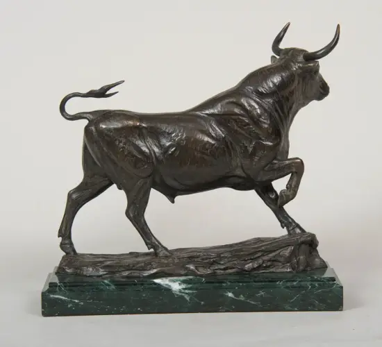 Bronze bull statue in mid-stride on a dark green marble plinth with a textured base.