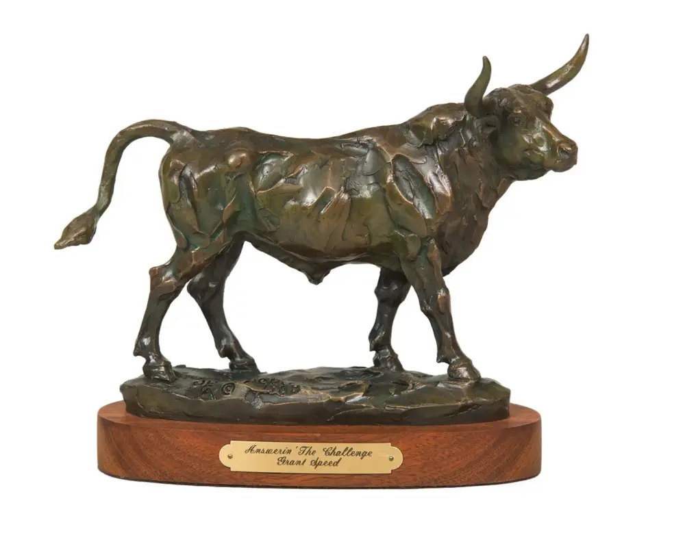 Bronze bull sculpture with a textured surface on a wooden base, serving as an award trophy edge plaque visible below.