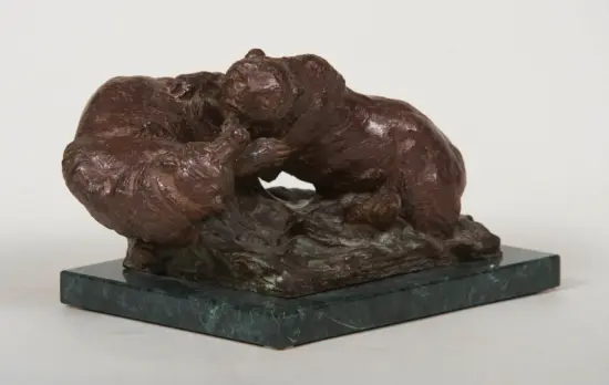 Bronze sculpture of two abstract intertwined figures embracing on a dark green marble base.