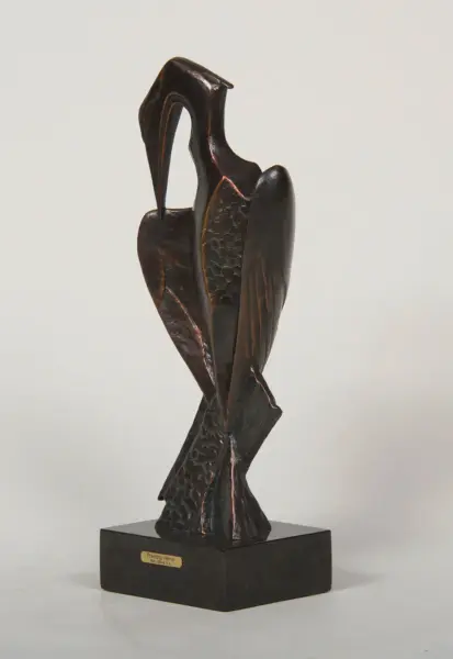 Bronze abstract sculpture of a heron standing on a black base, with a plaque reading 'Peering Heron'.