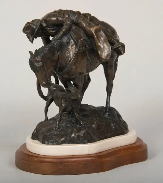 Bronze sculpture of a horse and rider rearing over a rocky base, with a small figure (dog) at the front, mounted on a wooden plinth.
