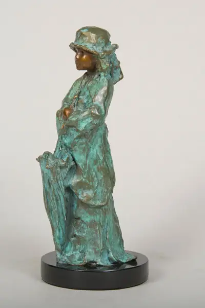 Bronze-green sculpture of a cloaked figure with a hat, standing and gazing to the left on a black circular base.