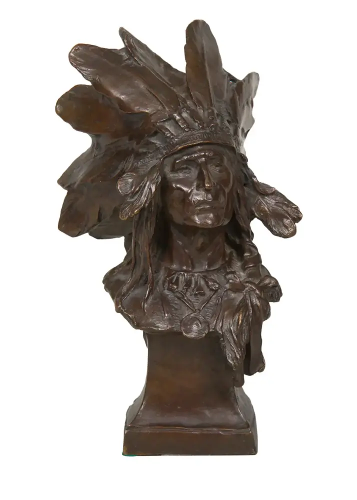 Bronze bust sculpture of a Native American man wearing a feathered headdress on a square pedestal.