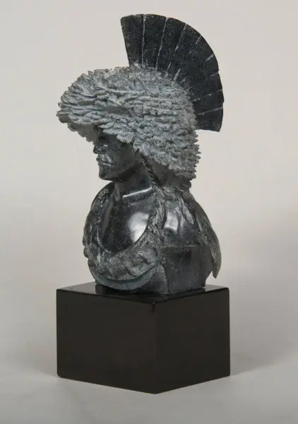 Dark stone bust of a woman wearing a large feathered headdress on a black pedestal base
