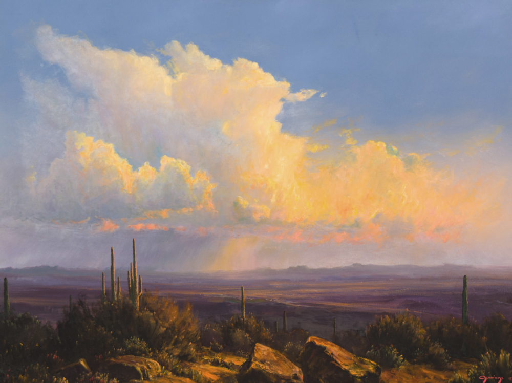 Desert landscape at sunset with tall cacti and rocky foreground under a dramatic, colorful cloud-filled sky