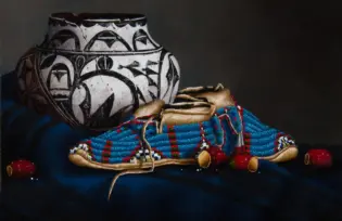A large black-and-white patterned ceramic vase rests beside a colorful beaded fabric with red berries and tan leather moccasins in a still-life composition.