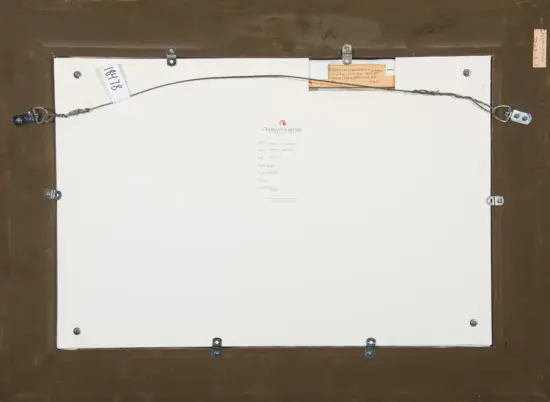 Back of a framed artwork showing a metal hanging wire, corner eyelets, and a white backing panel with a small gallery label in the center and notes taped near the top edge.