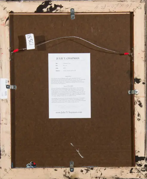 Back of a framed artwork showing a brown board, hanging wire, and metal brackets; a white label reads 'JULIE T. CHAPMAN' with details and a website at the bottom.