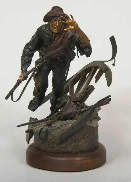 Bronze sculpture of a rugged adventurer in a hat with a whip, stepping over debris on a round wooden base.