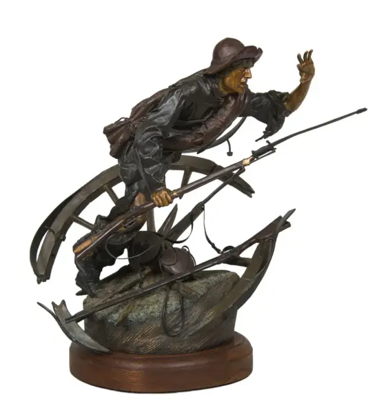 Bronze sculpture of a frontiersman in a hat, leaning forward and holding a rifle, mounted on a rocky pedestal with a wooden base.