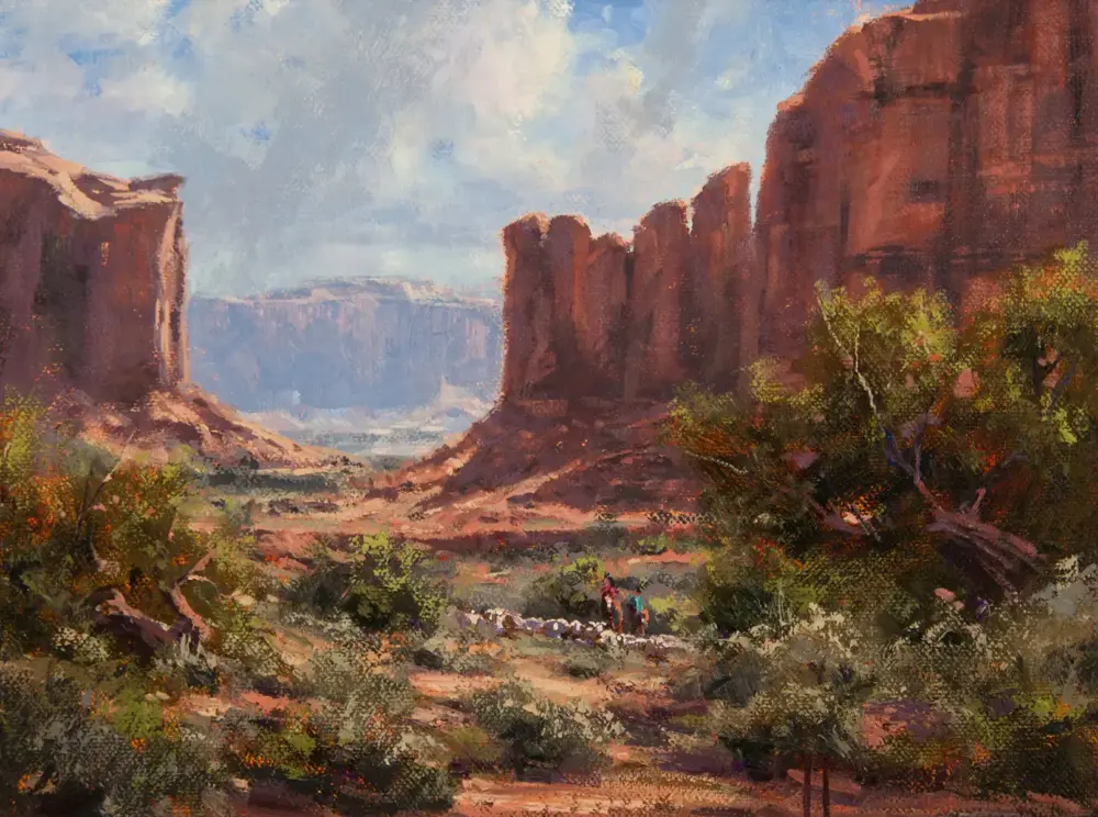 Painted desert canyon with tall red cliffs, scrubby vegetation, and two hikers in the foreground.